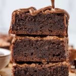 Stack of brownies with a spoon drizzling Nutella over top