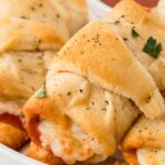 A white plate of the pizza rolls with pizza sauce on the side