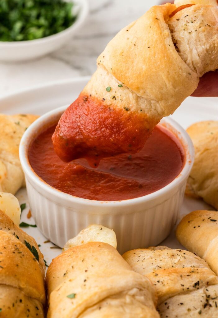 A pizza roll being dipped into pizza sauce