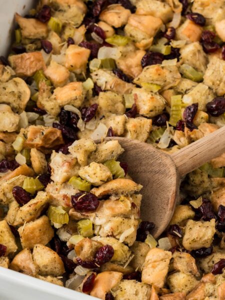 A casserole dish of stuffing with a serving spoon