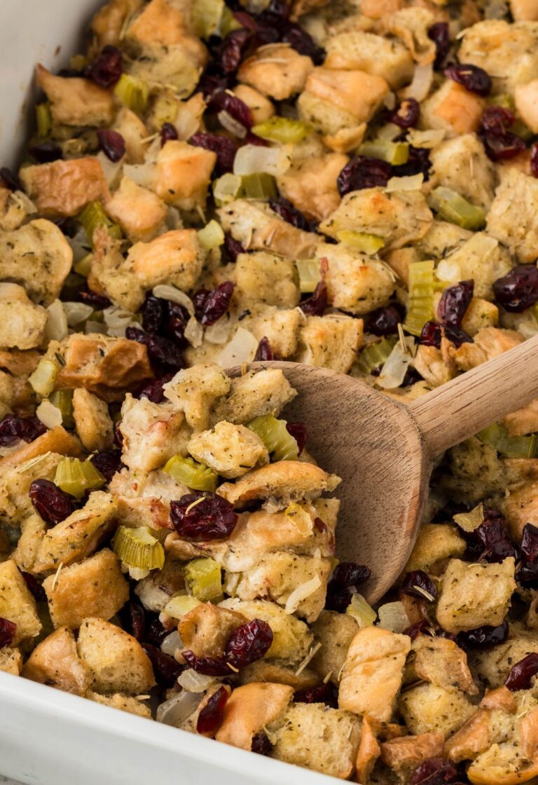 A casserole dish of stuffing with a serving spoon