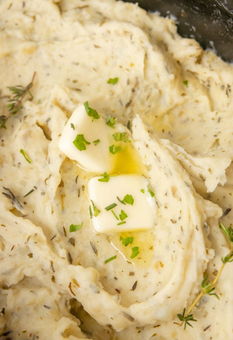 Inside of the slow cooker with mashed potato and butter.