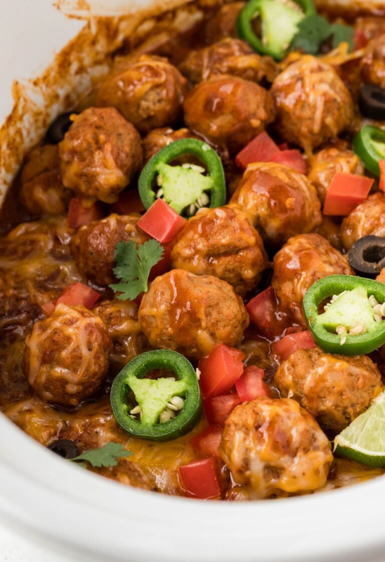 A slow cooker with meatballs inside of it