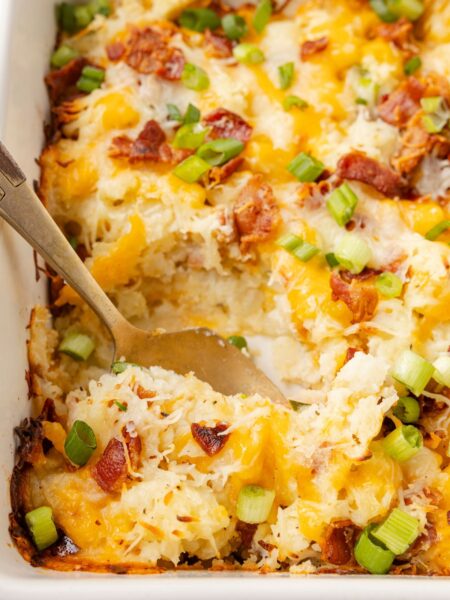 A baking dish with potato casserole and a serving spoon