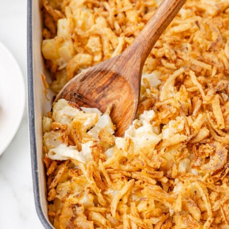 The baked casserole with a serving spoon inside of it.