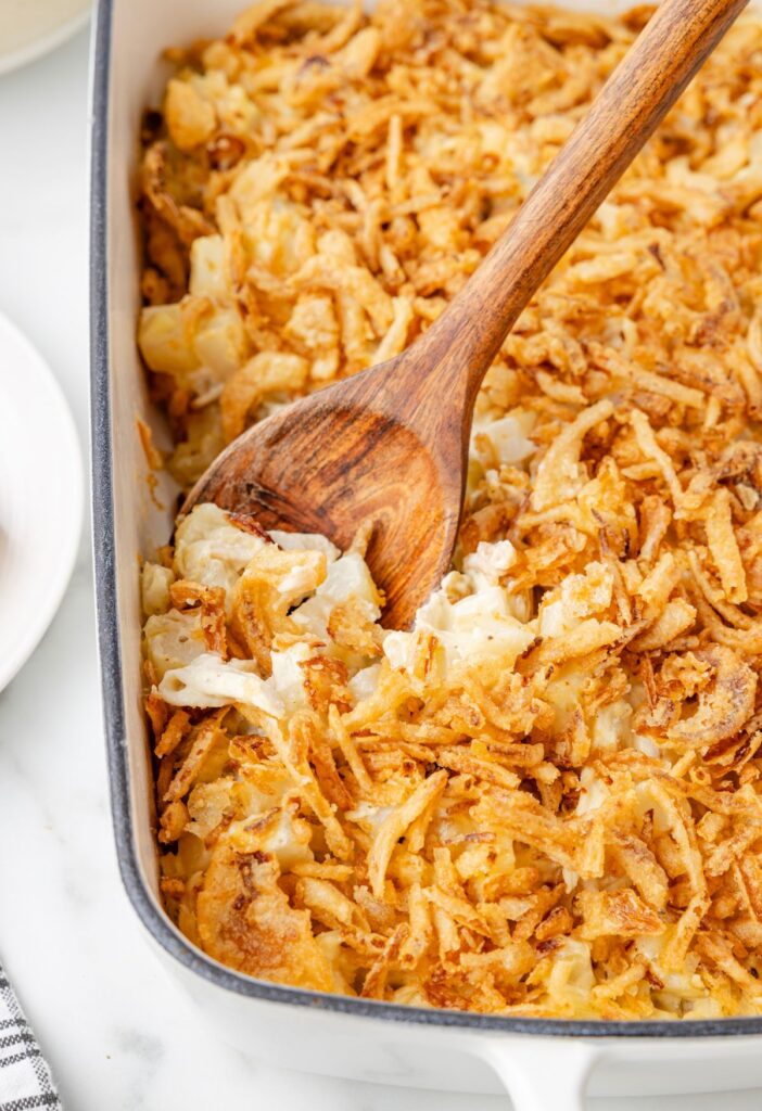 The baked casserole with a serving spoon inside of it. 