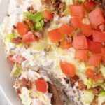 A bowl of the blt dip with a wooden spoon in it