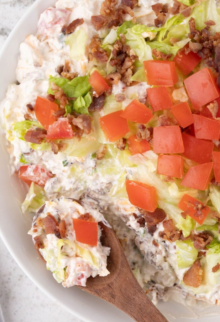 A bowl of the blt dip with a wooden spoon in it