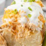 A baked potato cut in half with buffalo chicken topping