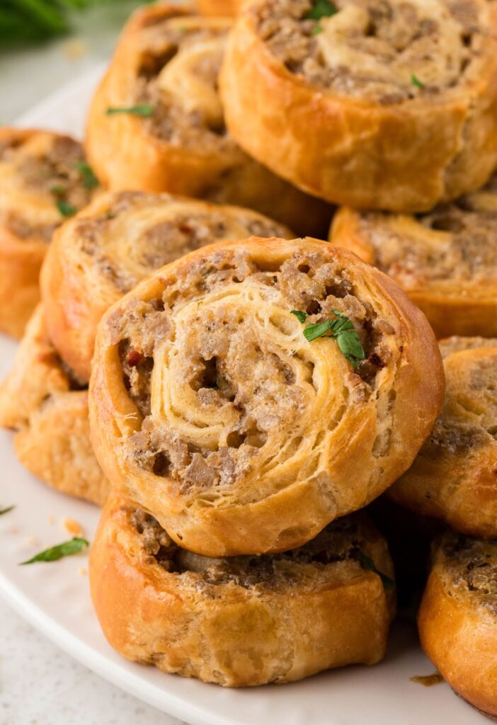 Sausage pinwheels stacked on a white plate