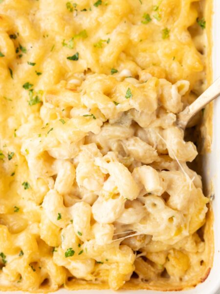 A casserole pan of Mac and cheese, with a serving spoon in it.