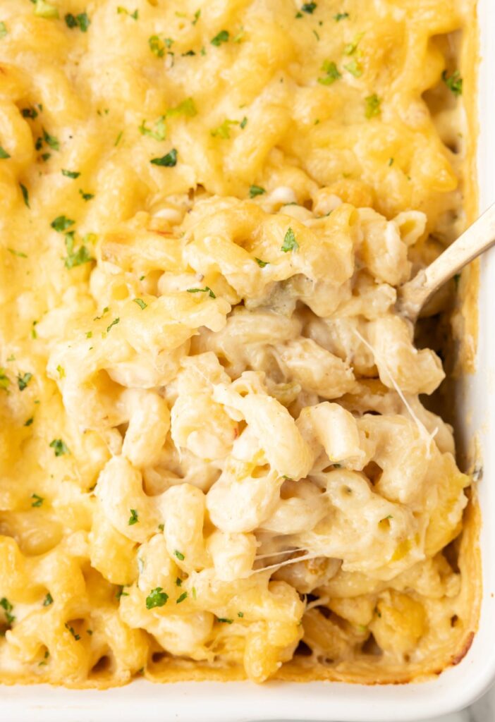 A casserole pan of Mac and cheese, with a serving spoon in it.