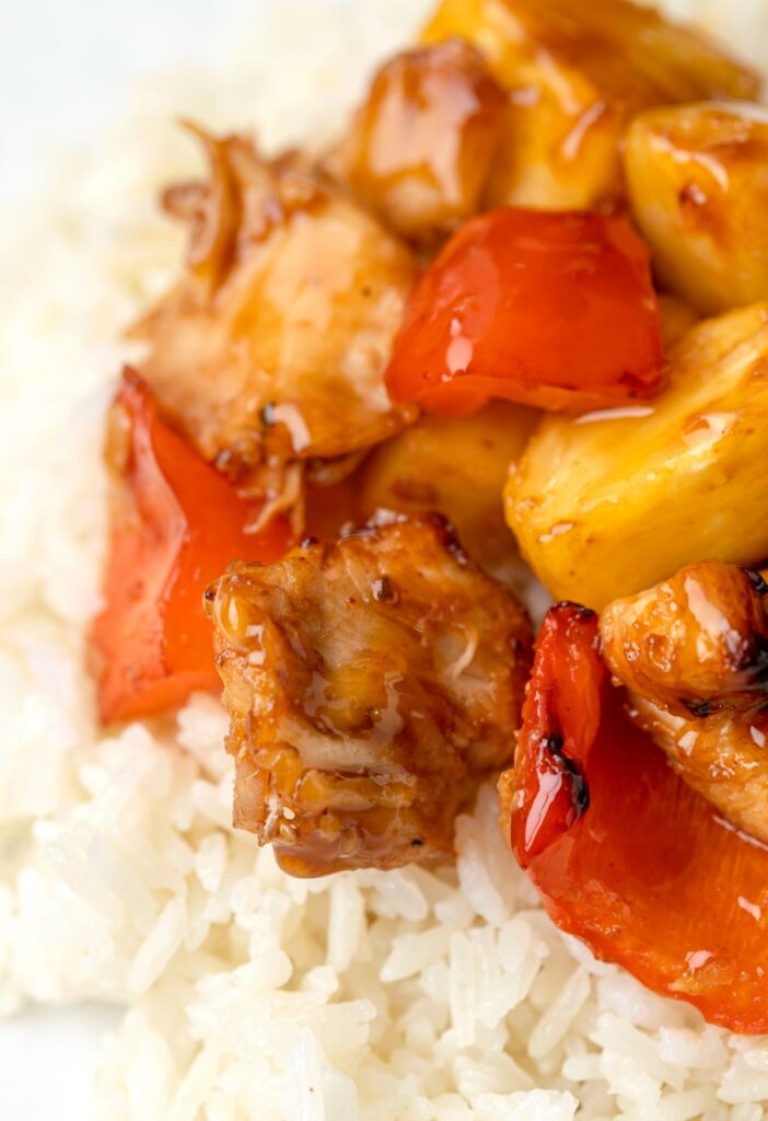 White rice topped with glazed pineapple chicken on top
