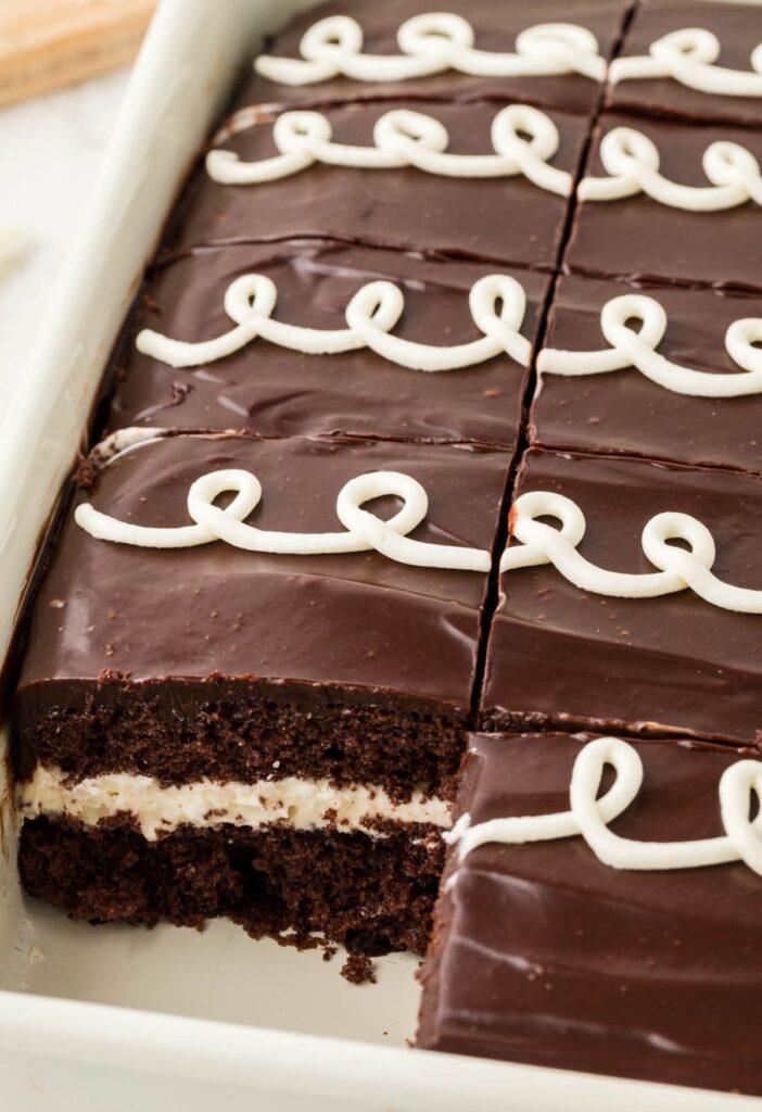 A pan of a baked hostess cake with a piece gone to see the center of the cake.
