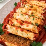 A cooked meatloaf on a platter that is sliced.