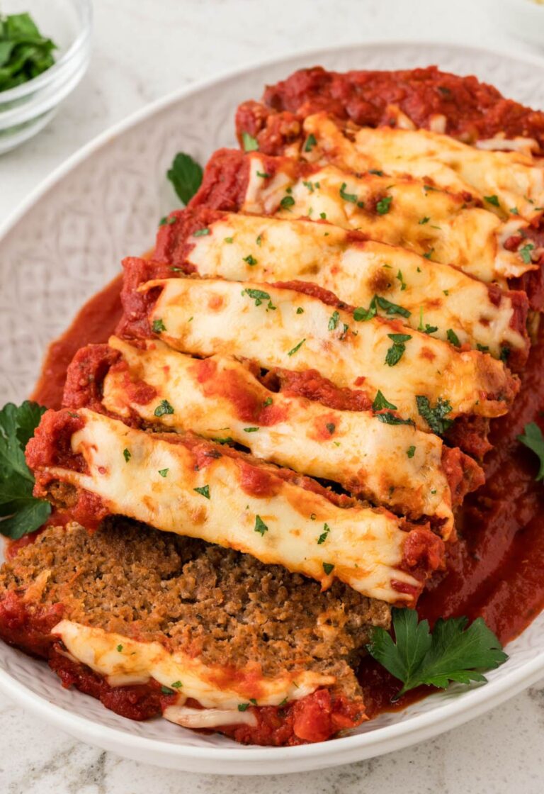 A cooked meatloaf on a platter that is sliced.
