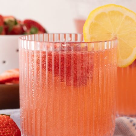 A glass of pink strawberry punch with a lemon slice