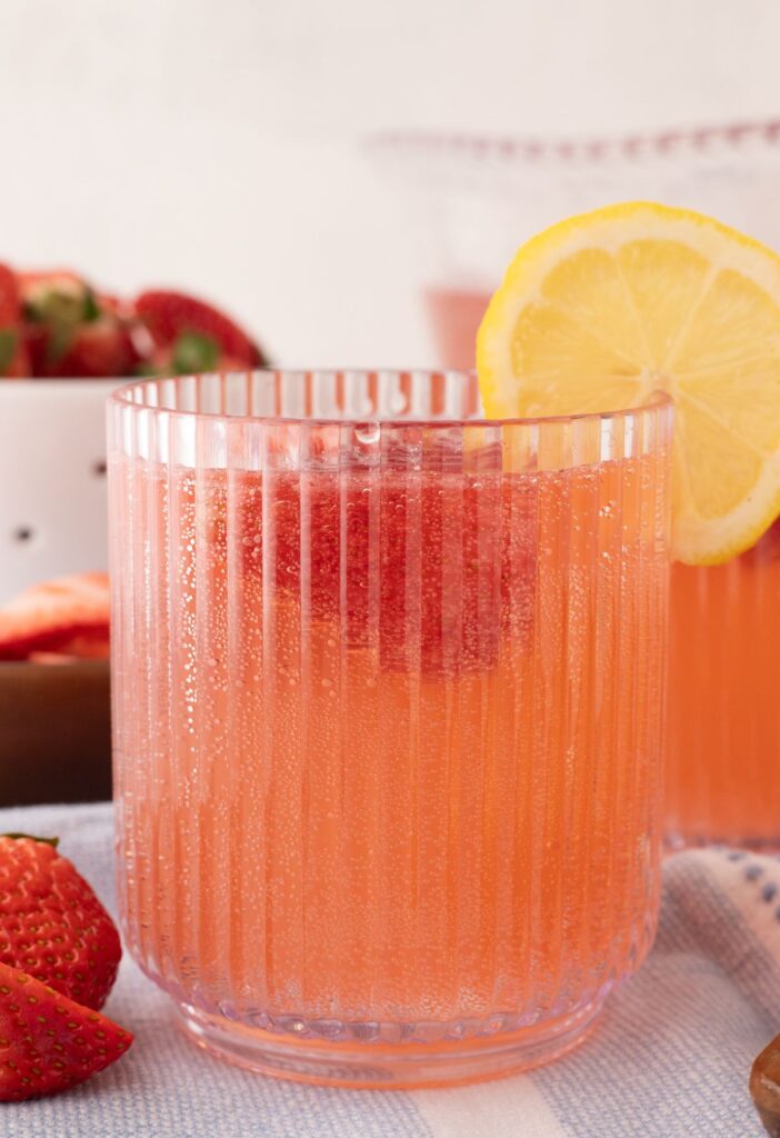 A glass of pink strawberry punch with a lemon slice