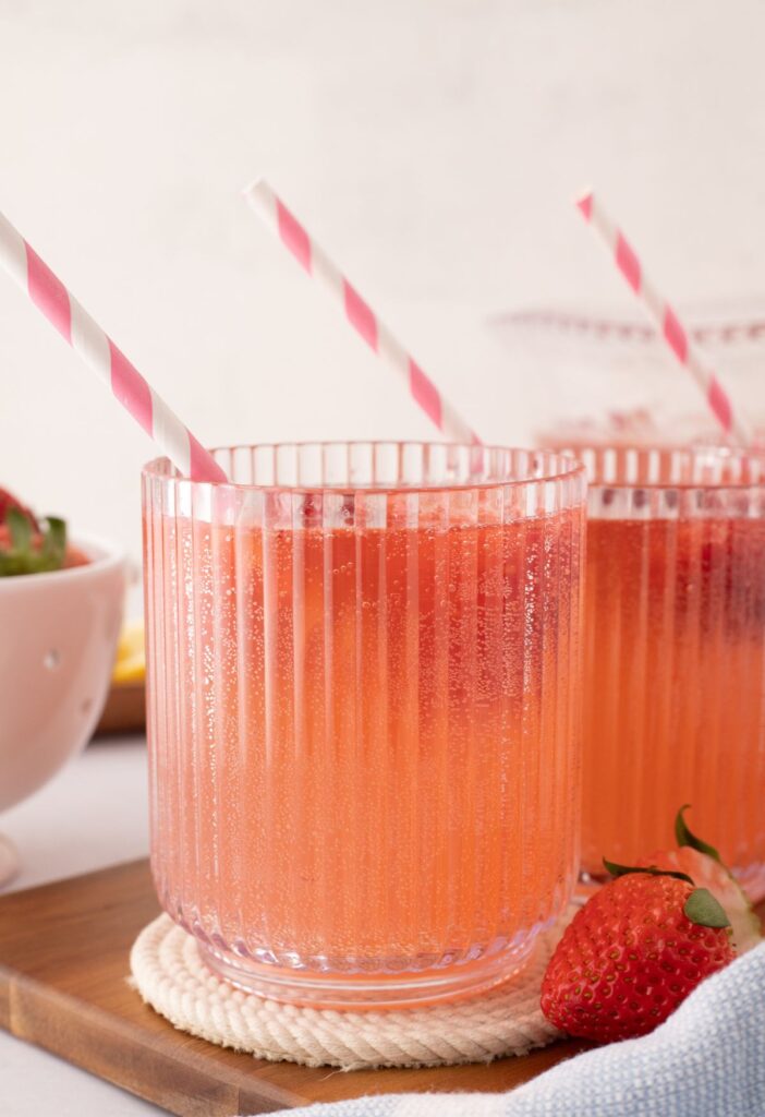 Cup of punch with a pink and white straw in it.