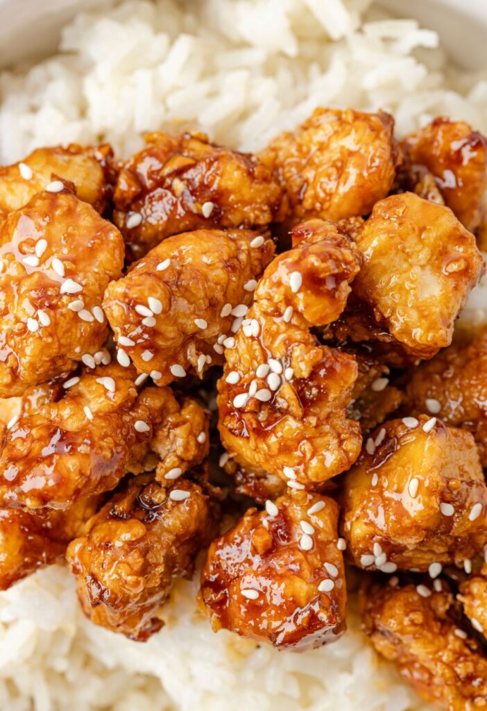 Cooked white rice topped with crispy chicken pieces in a sweet and sticky sauce. 