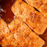 A stainless steel skillet with cooked and seared salmon inside of it.