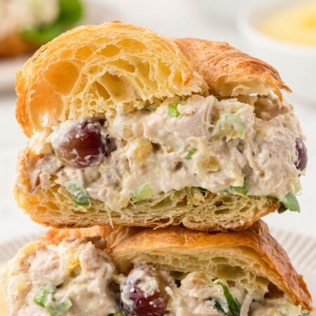A croissant with chicken salad cut in half and stacked on top of each other.