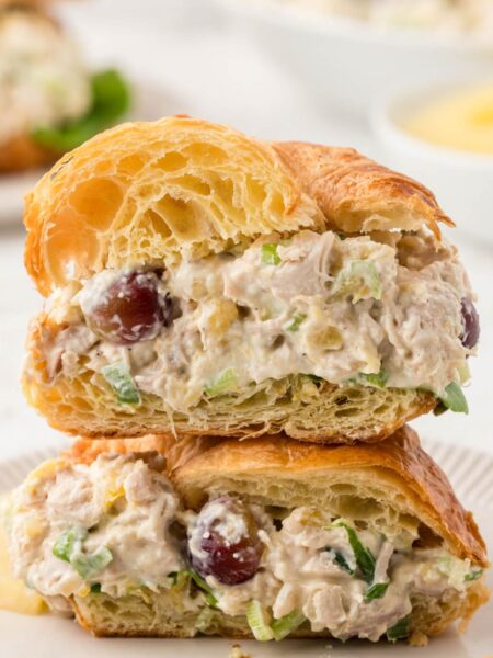 A croissant with chicken salad cut in half and stacked on top of each other.