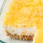 A pan of the layered pineapple jello recipe with a pretzel crust.