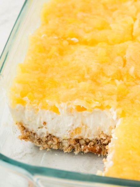 A pan of the layered pineapple jello recipe with a pretzel crust.