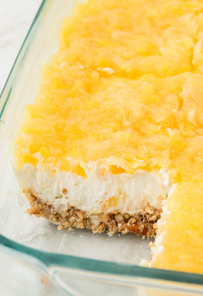 A pan of the layered pineapple jello recipe with a pretzel crust. 
