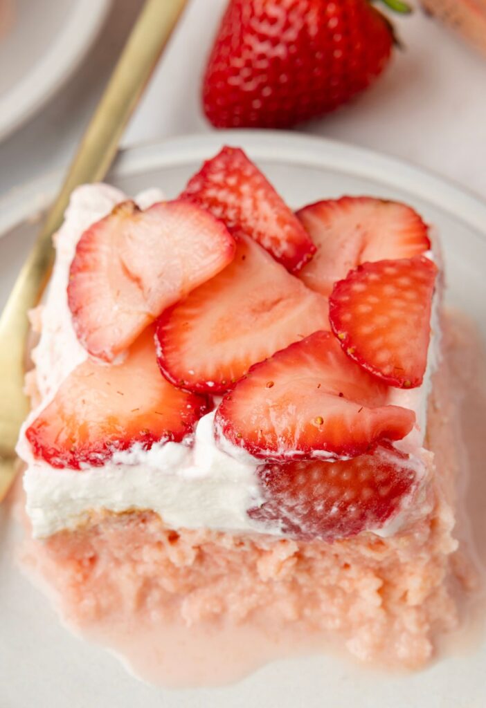 A slice of tres leches cake with strawberries on top