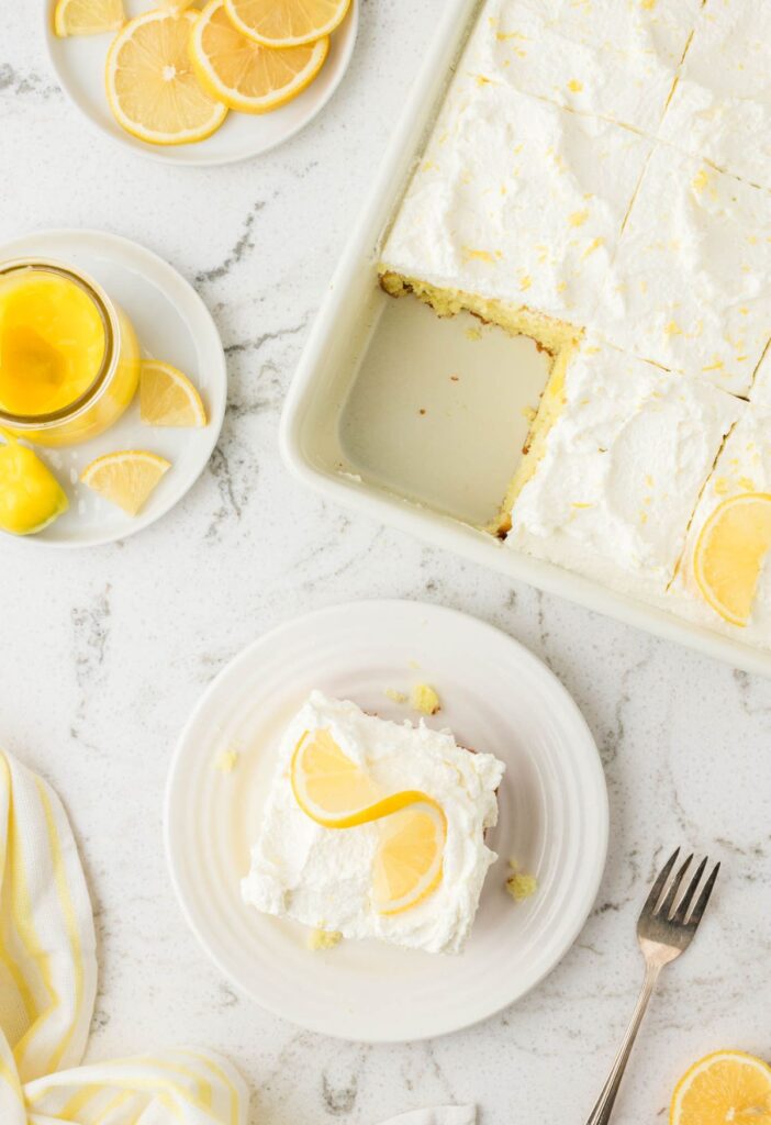 hero shot of the pan of poke cake with a serving plate with a slice on it. 