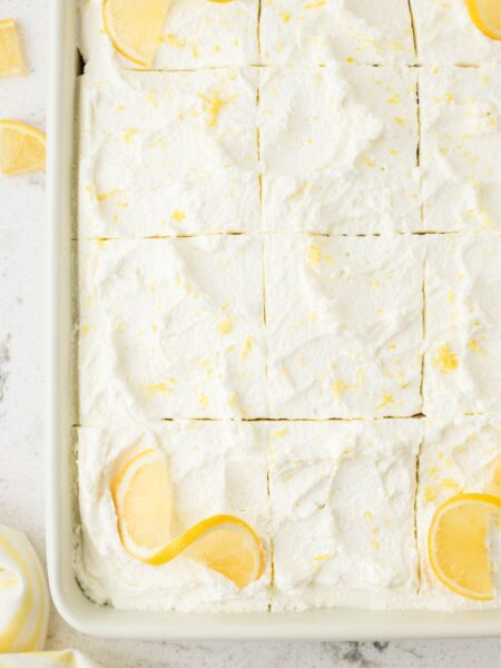 Overhead pic of the lemon poke cake with whipped cream on top and lemon slices.