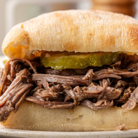 Side view of the pulled beef sandwich on a stack of plates.