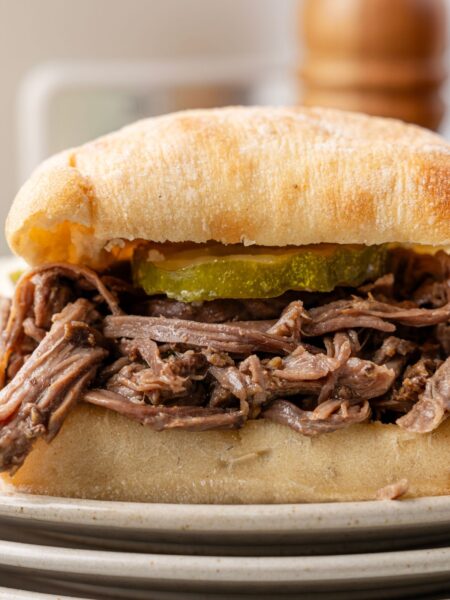Side view of the pulled beef sandwich on a stack of plates.