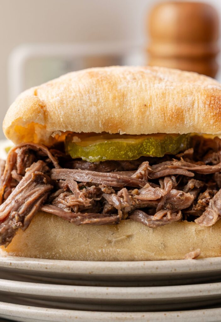 Side view of the pulled beef sandwich on a stack of plates.