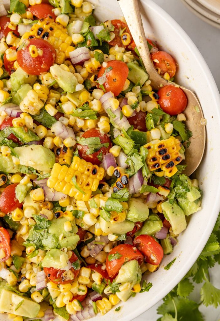 A serving bowl of the charred corn and avocado salad