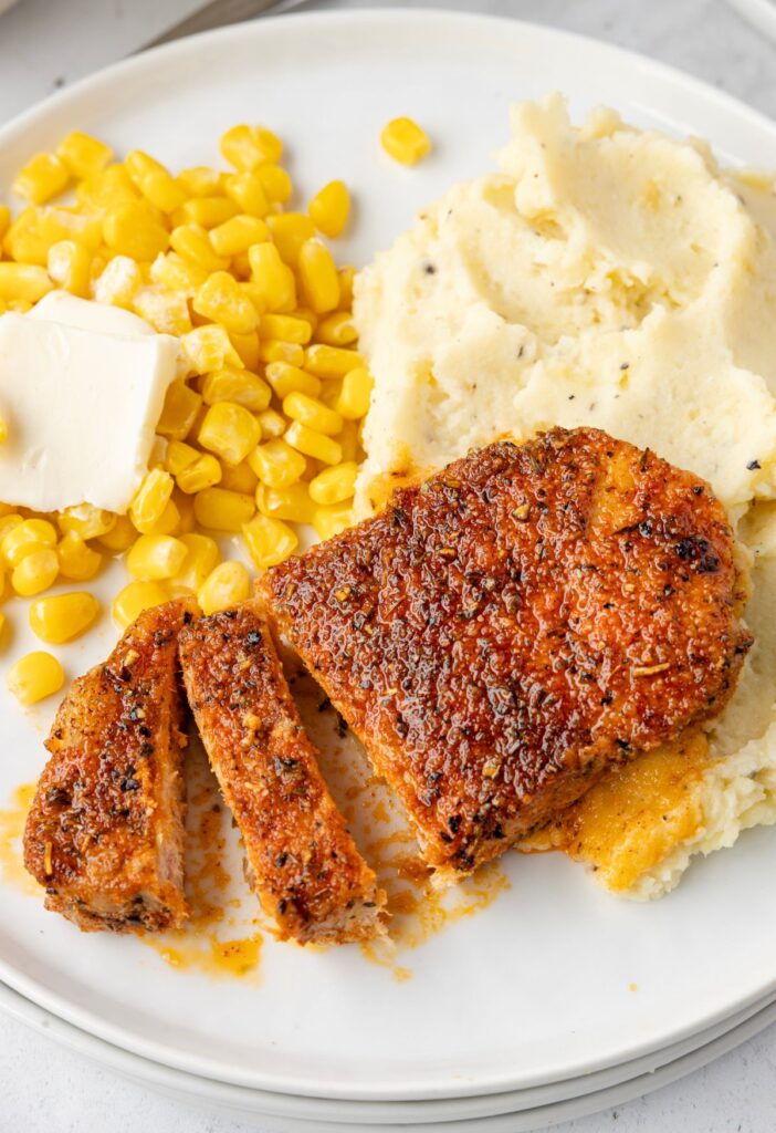 Serving plate of the pork with potatoes and corn.