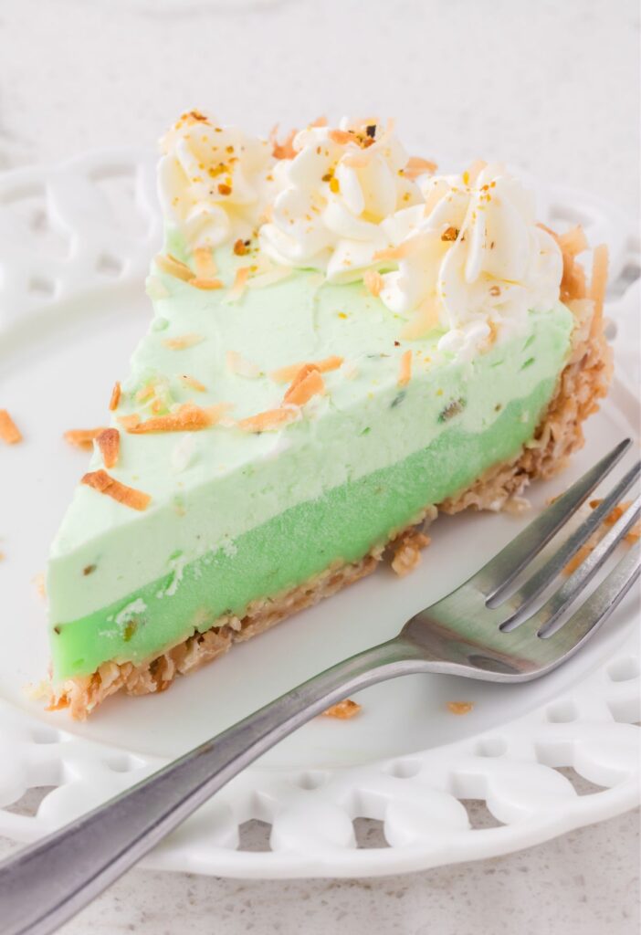 Slice of coconut pistachio pie on a plate with a fork. 