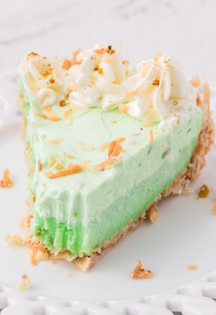 A slice of the pistachio coconut pie on a plate with a fork. 
