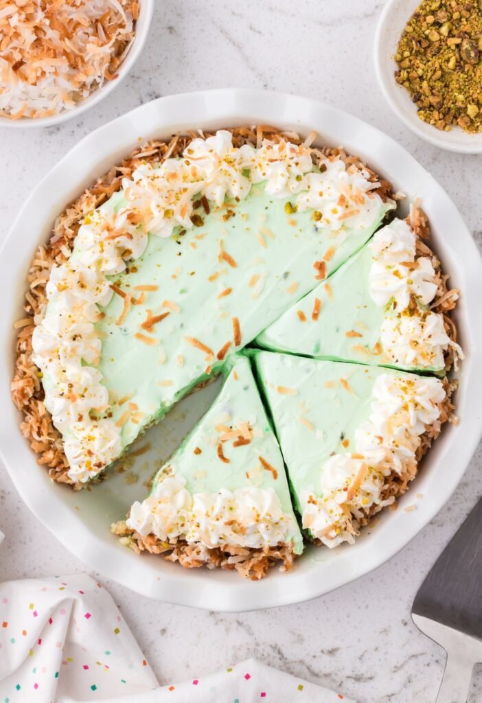 Top view of the pistachio pudding pie with coconut on top and cut into slices. 