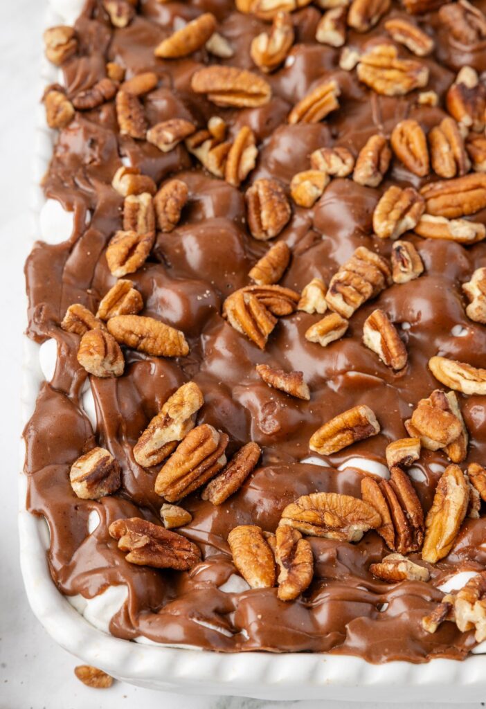 Mississippi Mud Cake inside the white baking pan with pecans and chocolate on top.
