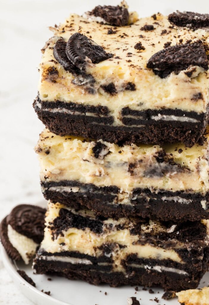 Stack of oreo cheesecake bars on a white plate.
