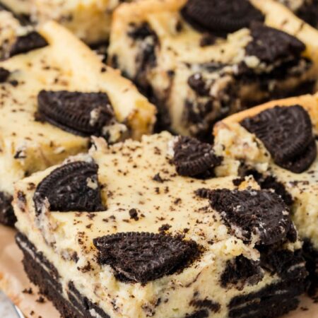 Side view of oreo cheesecake bars on a cooling rack on top of parchment paper.