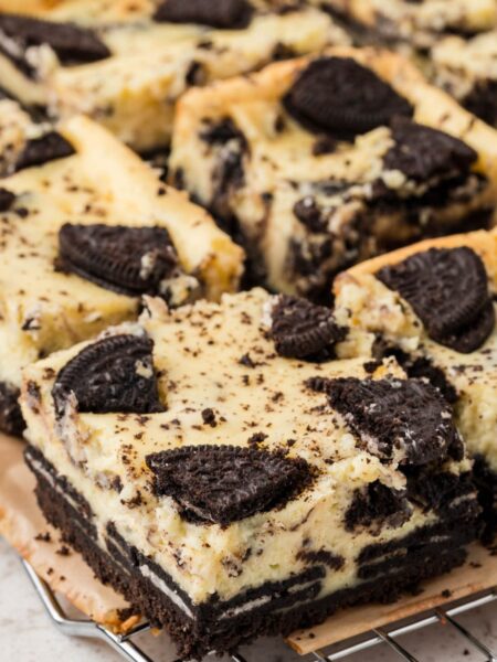 Side view of oreo cheesecake bars on a cooling rack on top of parchment paper.