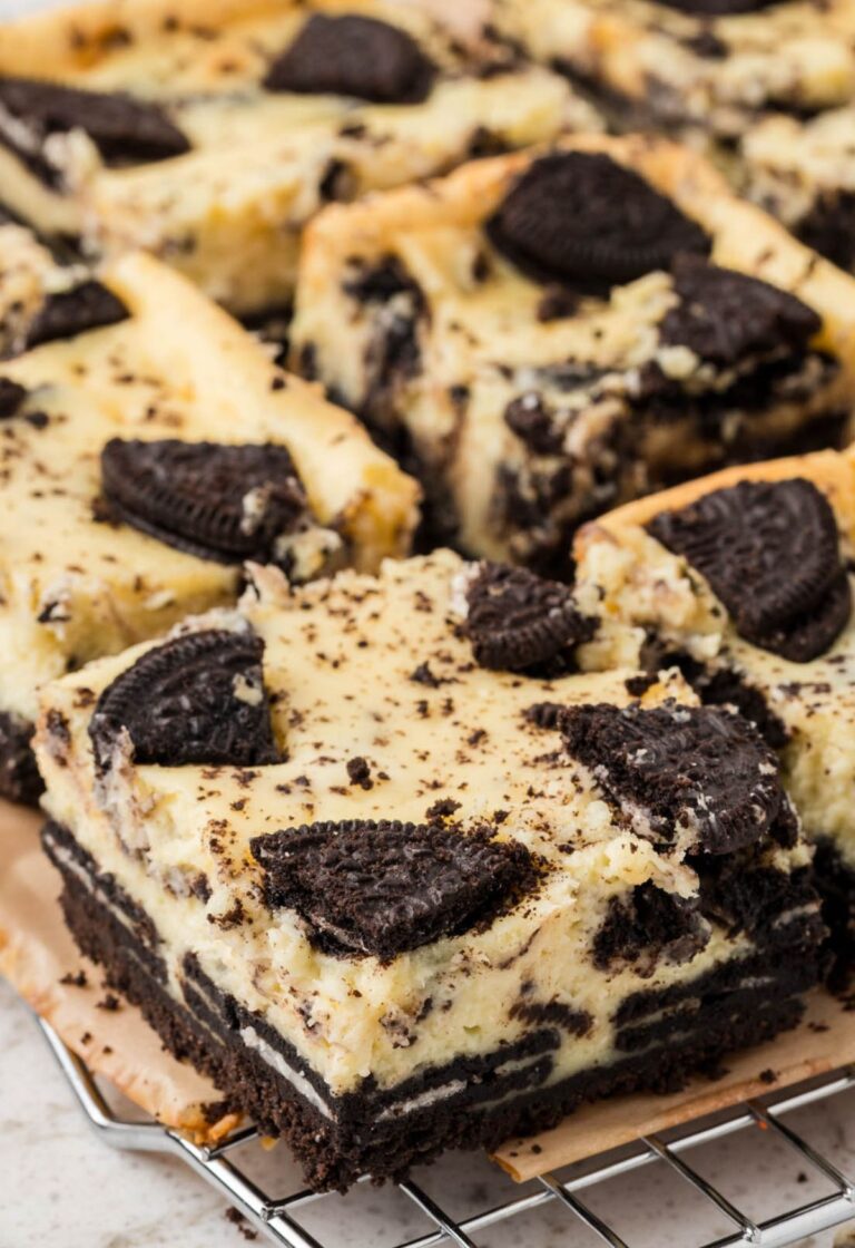 Side view of oreo cheesecake bars on a cooling rack on top of parchment paper.