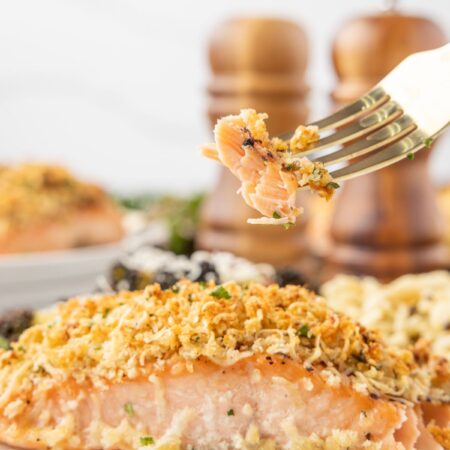 A salmon filet on a white plate with a fork.