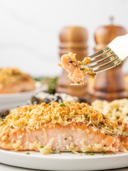 A salmon filet on a white plate with a fork.