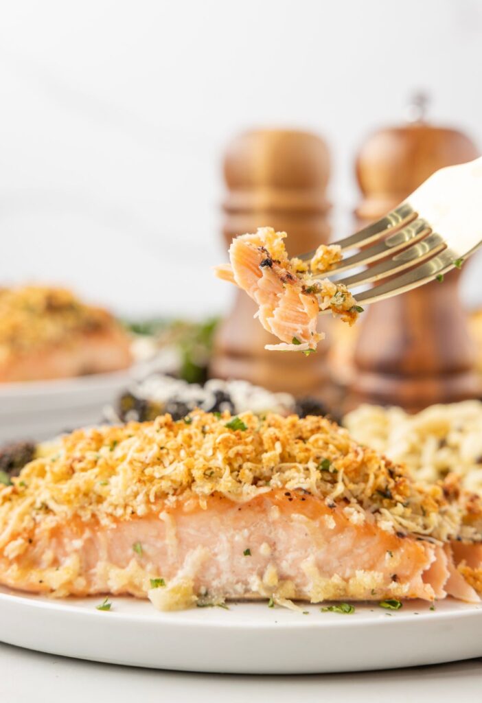 A salmon filet on a white plate with a fork. 