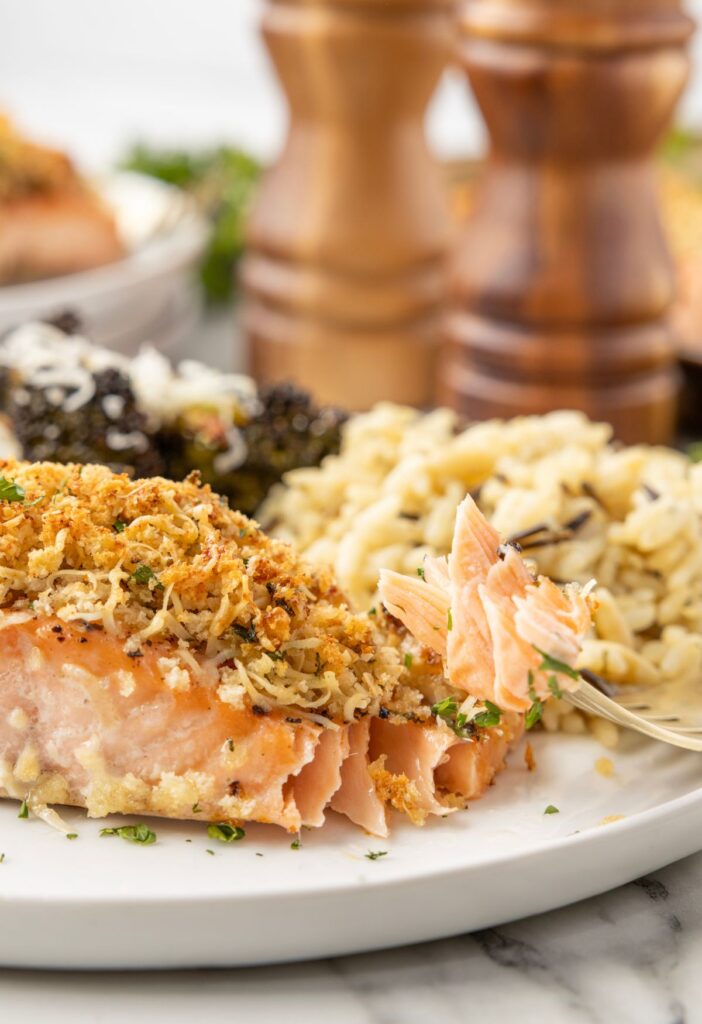 A piece of cooked salmon filet with a fork taking a bite from it. 